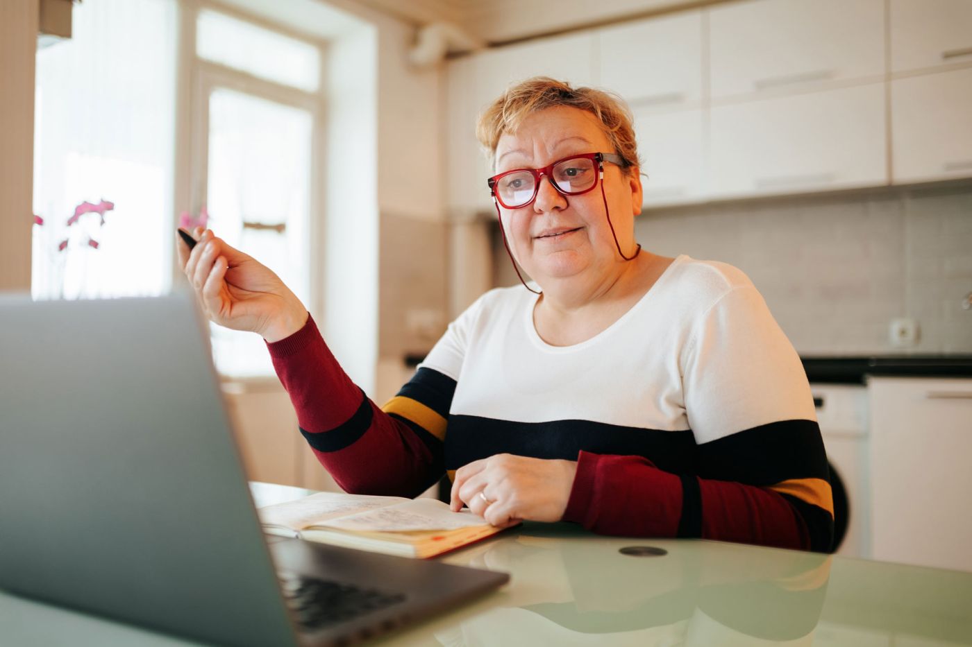 Frau mit Brille an einem Tisch vor einem Laptop